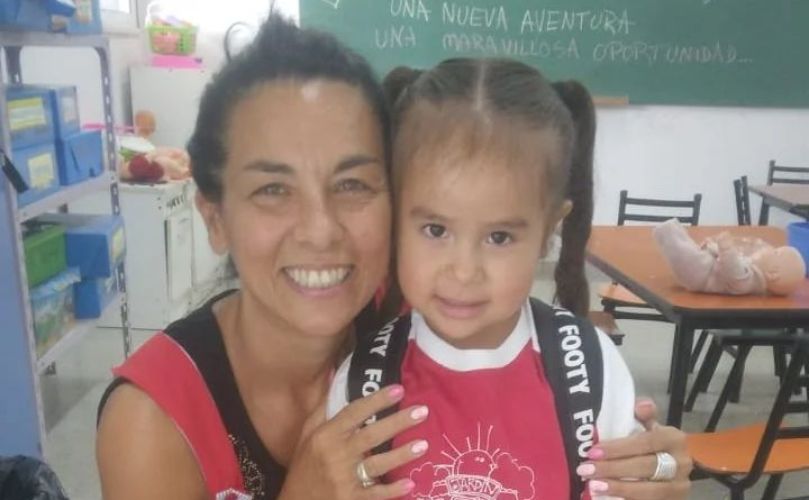 La pequeña junto a una de sus maestras